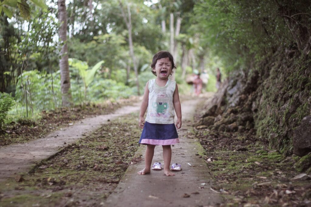 child standing outside with no shoes crying