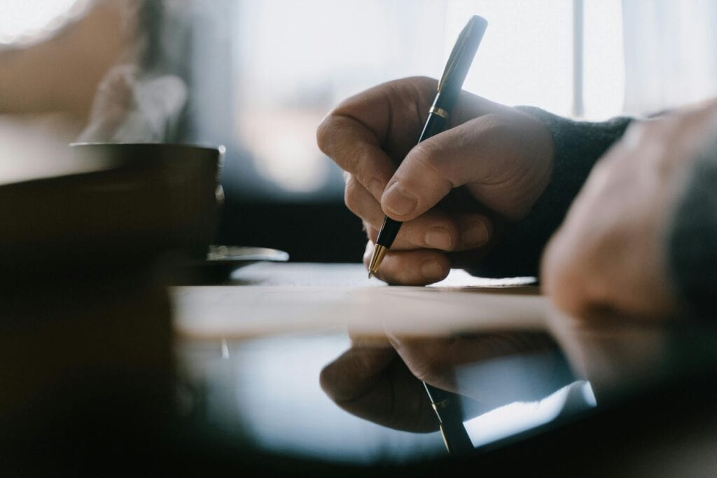 man's hand writing letter