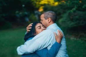 A couple embraces tenderly in a peaceful outdoor setting, reflecting the emotional journey of being diagnosed with cancer and finding strength together.