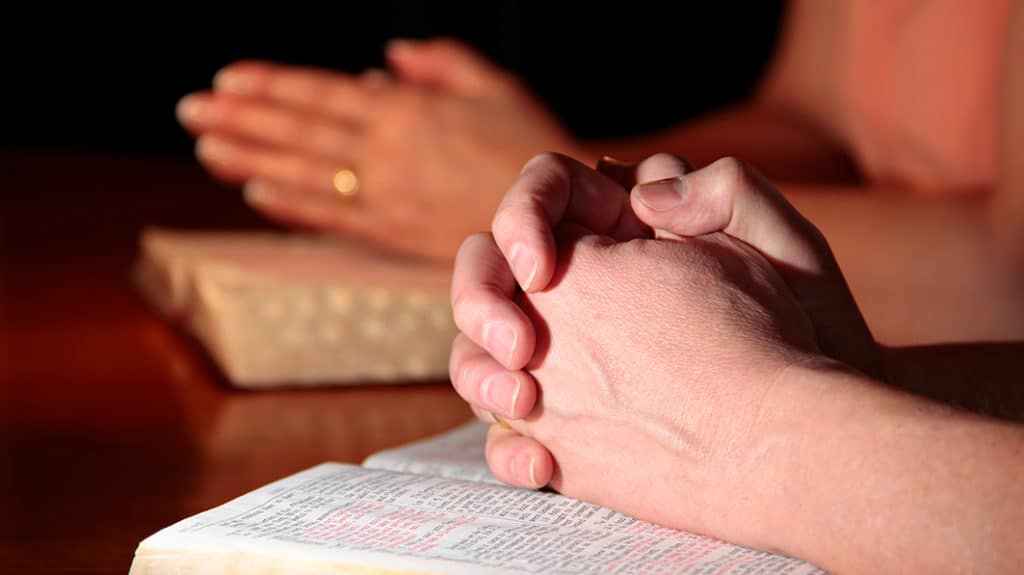 Man and Woman Praying with Holy Bibles