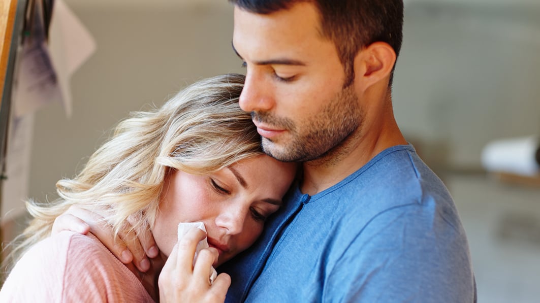 a woman cries on her husband's chest