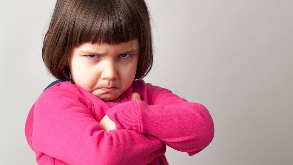 angry toddler crosses her arms