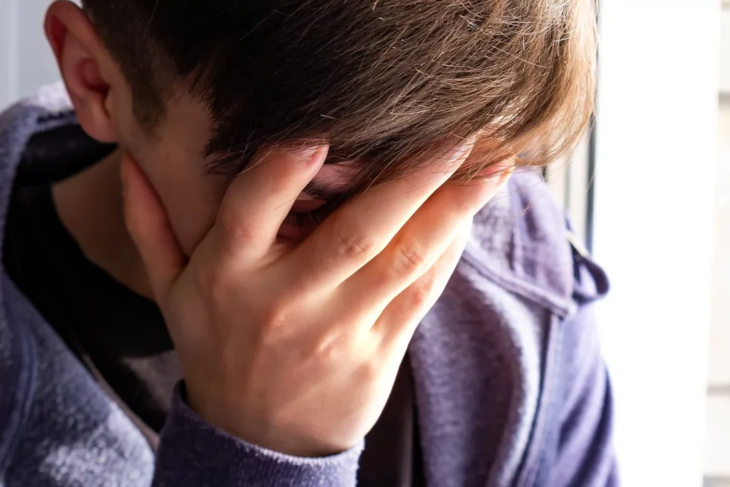 middle school boy with hand over face in embarrassment