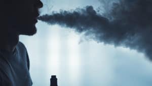 A bearded man in the clouds of steam from electronic cigarette closeup. vaping man