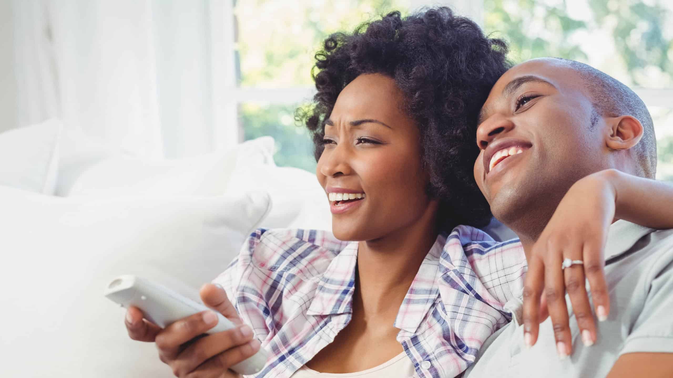 A couple laughs while watching TV