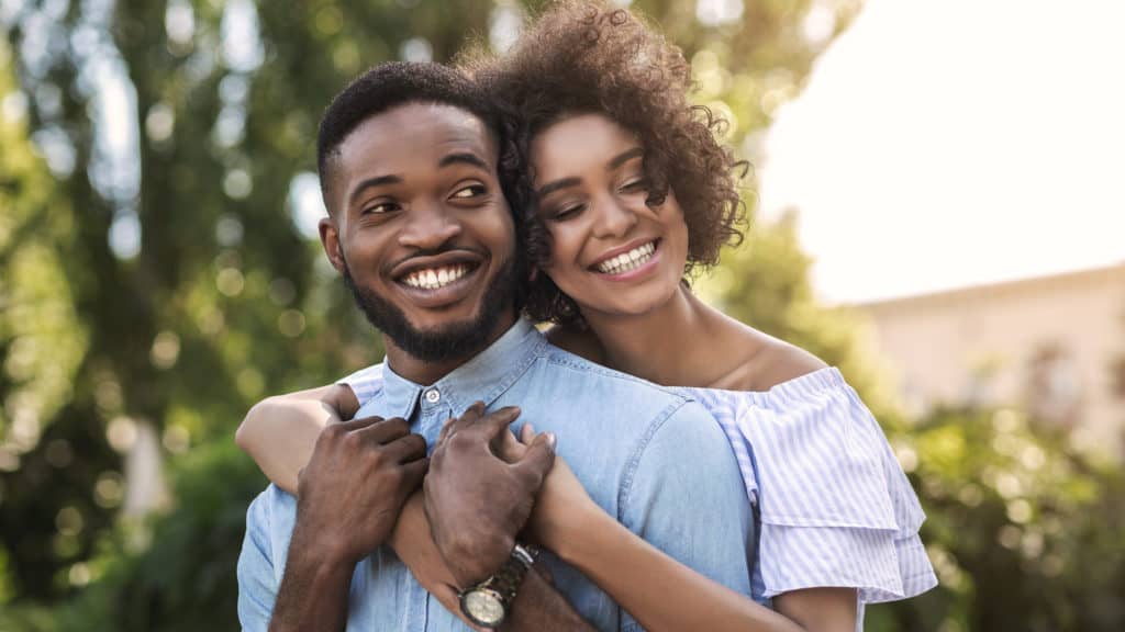 Wife wrapping arms around husband outside
