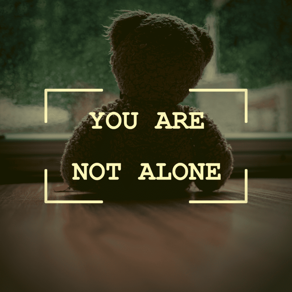 Teddy Bear with sign that says you are not alone when wondering what to say to someone who lost a child