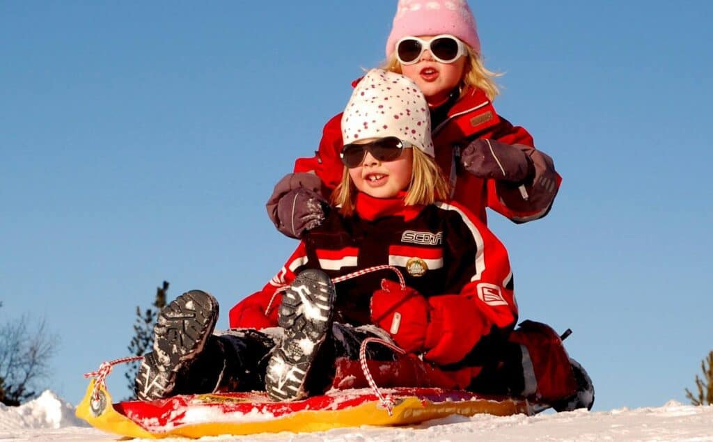 two girls on sled in winter snow