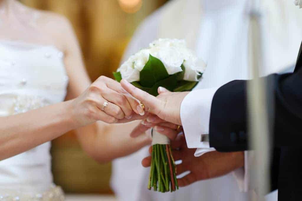 Bride putting a ring on groom's finger during wedding ceremony