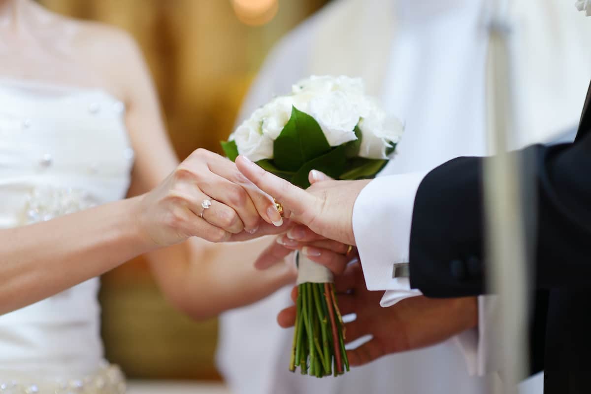 Bride putting a ring on groom's finger during wedding ceremony
