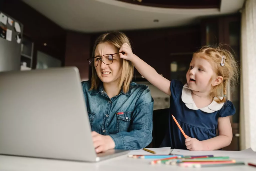 Homeschool parent sitting next to her daughter as she trys to remove her mom's glasses