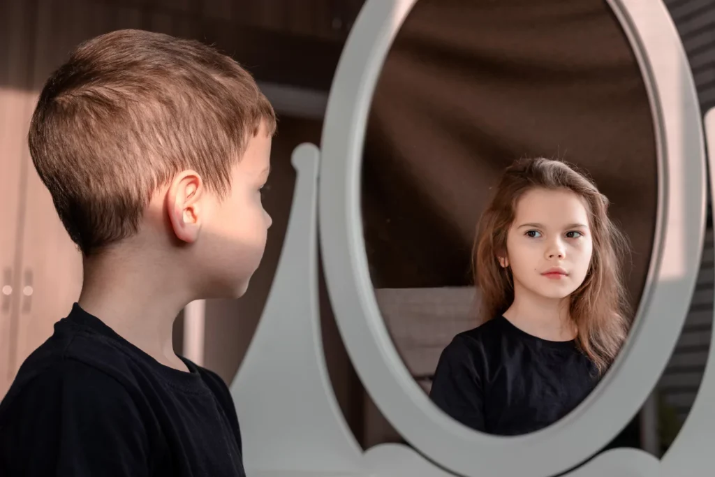 Boy looking into a mirror and seeing himself as a girl.