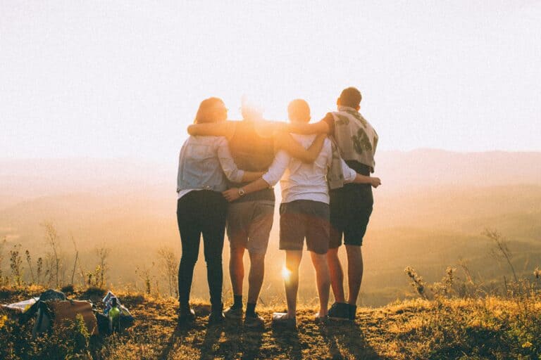This image shows four friends standing together with their arms around each other. What Does the Bible Say About Friendship?
